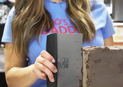 Miesha Tate con raschietti da banco e tagliapasta per decorare una torta al cioccolato quadrata Fat Daddio's Cucina di prova