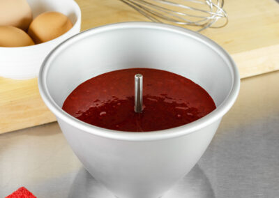 Heating Core Rod within red velvet cake batter in a Dolly Varden doll cake pan in a bakery