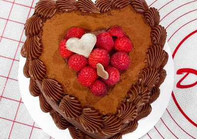 Tortiera con cuore di cioccolato decorata su un tappetino da lavoro in una panetteria