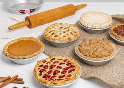 Assortment of Lemon Meringue, Pecan, Pumpkin, Apple, Cherry Pies in small pie pans in a bakery