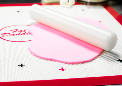 Rolling Rod with pink fondant on a Silicone Cookie Sheet Work Baking Mat in a bakery