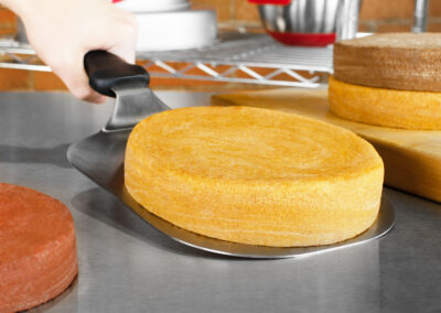 Serving Spatulas with yellow cake layer surrounded by cake layers in a brick bakery