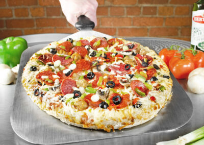 Serving Spatula pizza peel with pizza surrounded by cake layers in a brick pizzeria restaurant