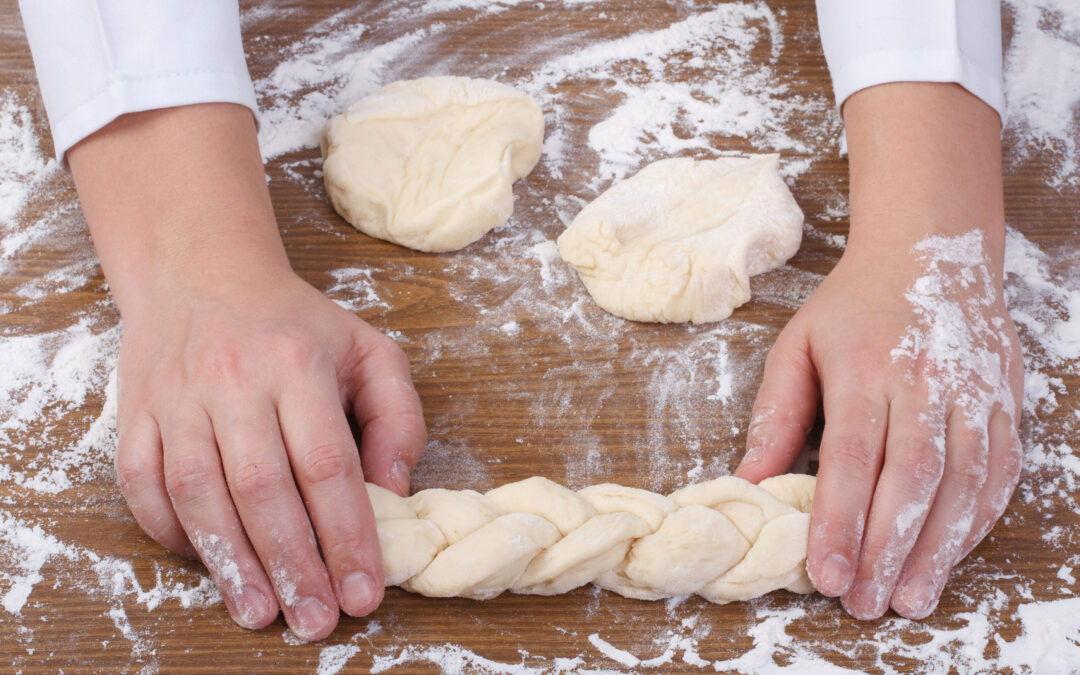 Baker weaving bread dough over flour
