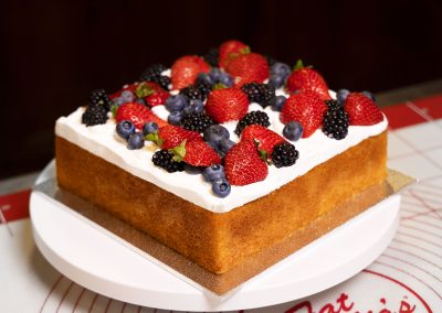 Square White Naked Cake with fruit in a bakery
