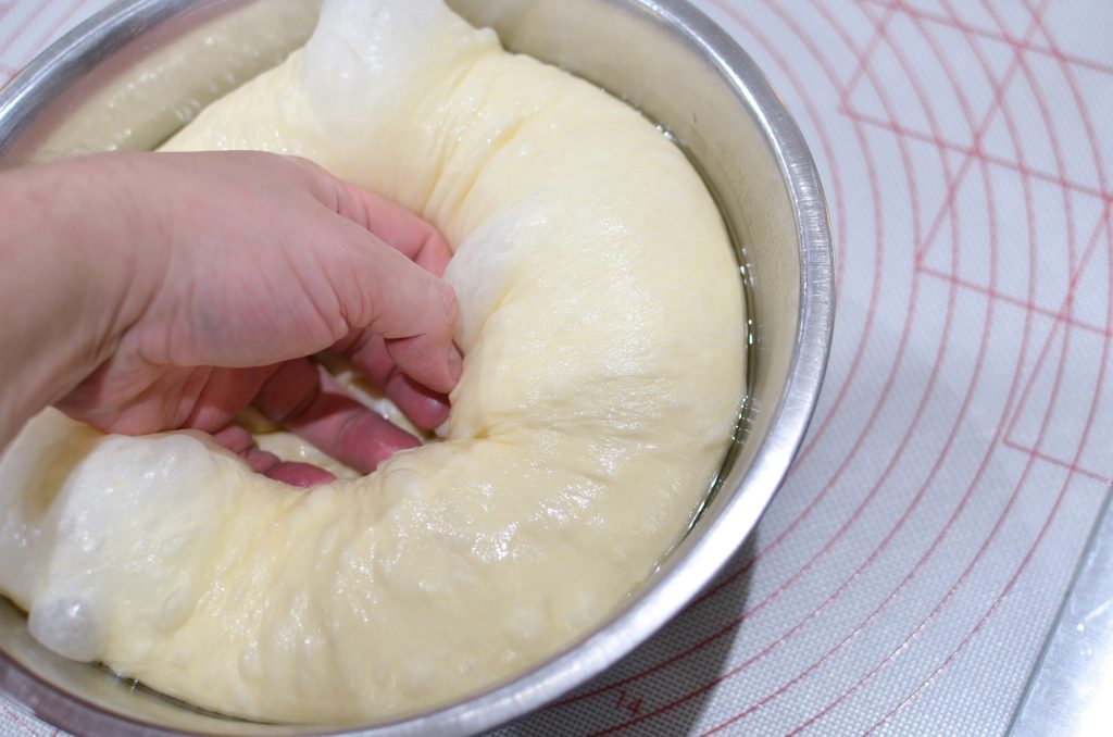 dough proofing in a bowl then punched down using a fist