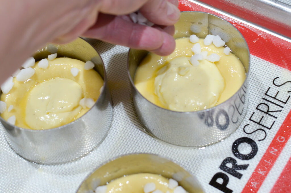 A baker decorating Torta Della Nonna dough in pastry rings on a work mat